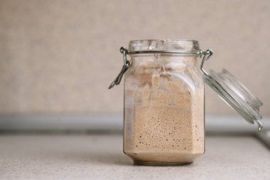 Kırsal bir kavanozda faal ekşi mayalı çavdar ekmeği. Dikey oryantasyon, ön görüş. Ev yapımı ekmek pişirmek için ekmek.