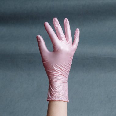 Gri bir arka planda pembe nitrile eldiven verin. Kare görünüm oranı