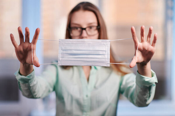 the girl holds a medical mask in her hands