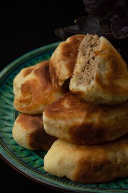 Yeşil tabakta kızarmış et ve fesleğen yakın plan. Bir turta kesimi. Siyah arkaplan.