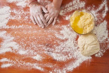 Tabakta yumurta ve hamur serpiştirilmiş un ile rendelenmiş peynir ve pişirmeye başlamadan önce ahşap bir masada genç bir aşçının elleri.