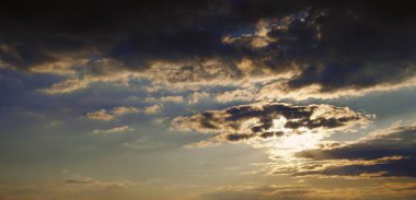 Güneşin desenli bulutların arkasına saklandığı güzel mavi günbatımı gökyüzünün panoramik fotoğrafı