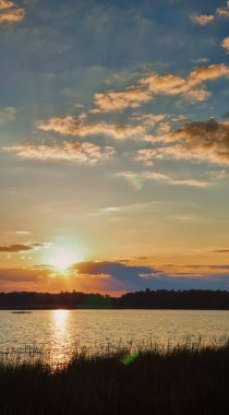 Güzel mavi günbatımı gökyüzünün dikey panoramik fotoğrafı. Bulutların arasından parlayan sarı bir güneş.