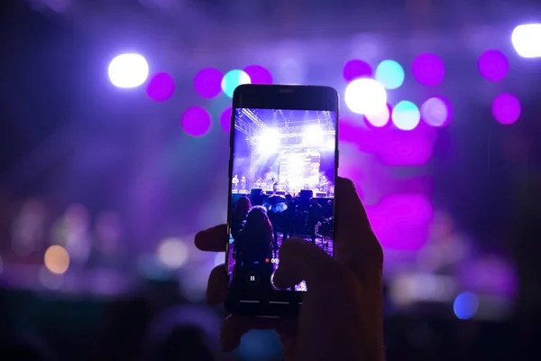 İnsanlar ellerinde akıllı telefonlar ve fotoğraf konseri tutuyorlar.