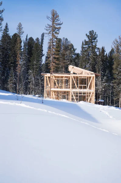 Na encosta de neve é uma casa de armação de madeira em um fundo de floresta . — Fotografia de Stock
