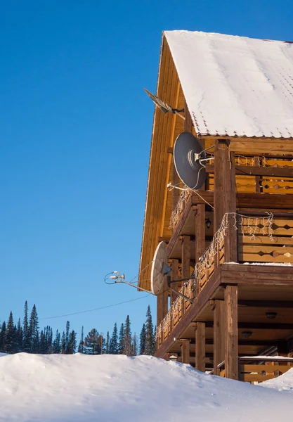 Casa de madeira com equipamento de satélite na floresta contra o céu . — Fotografia de Stock