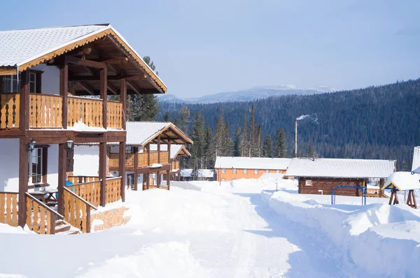 El asentamiento de la casa de baja altura está rodeado por un bosque de invierno . —  Fotos de Stock