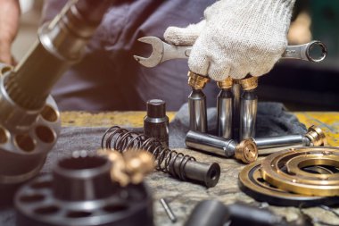 Profesyonel tamirci hidrolik piston pompasını sökmek için anahtar aletleri tutuyor. 