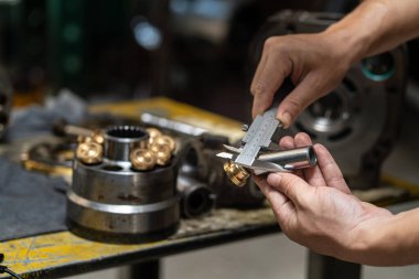 Profesyonel tamirci hidrolik pompanın pistonunu kontrol etmek ve ağır makineleri tamir etmek için tutuyor. 