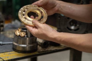 Profesyonel tamirci hidrolik piston pompasının kapak plakasını kontrol etmek ve ağır makineleri tamir etmek için tutuyor. 