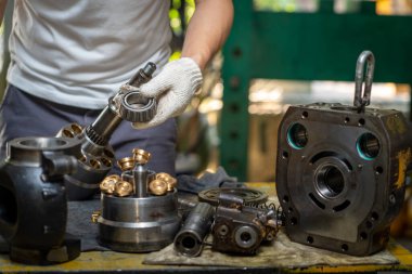 Hidrolik piston pompasını kontrol etmek ve ağır makineleri tamir etmek için tutan profesyonel tamirci. 