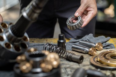 Hidrolik piston pompasını kontrol etmek ve ağır makineleri tamir etmek için tutan profesyonel tamirci. 