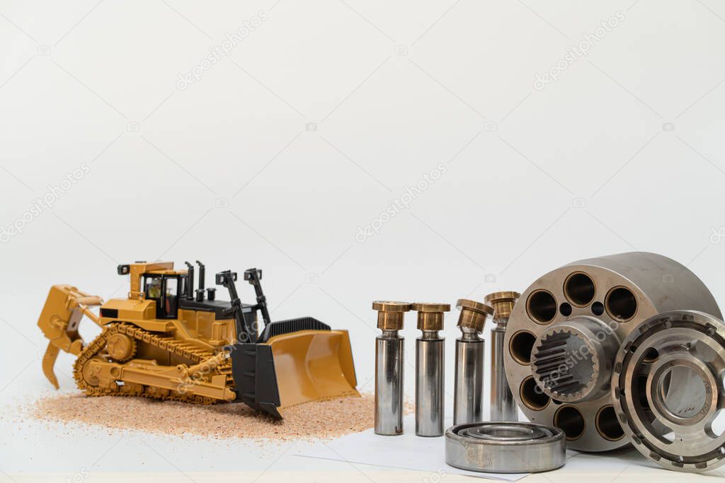 hydraulic piston pump parts with bulldozer tractor model on white background, repair maintenance heavy machinery concept 