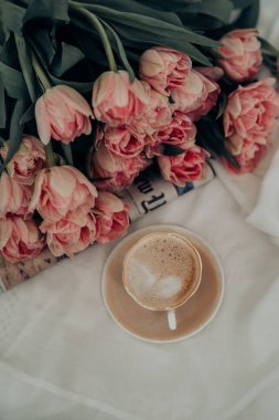 Lale çiçekleri, gazete ve beyaz arka planda bir fincan kahve. 