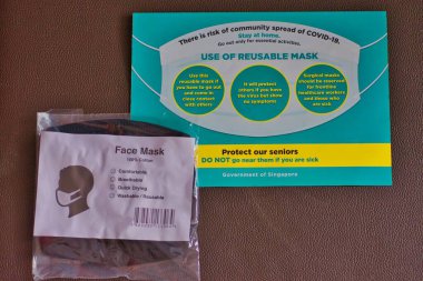 Yeniden kullanılabilir ve yıkanabilir yüz maskeleri, COVID-19 krizi sırasında Singapur otoritesi tarafından toplumun virüs yayılmasını önlemek için dağıtılır..