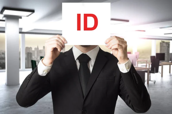 Businessman in suit hiding face behind sign id — Stock Photo, Image