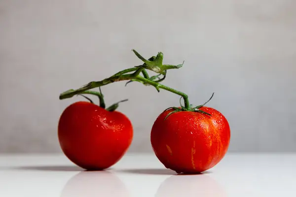 Gri arkaplanda beyaz bir masada kırmızı domatesler