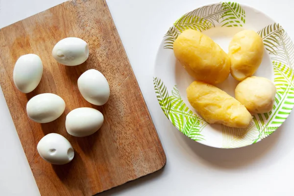 Haşlanmış yumurta ve haşlanmış patates beyaz bir masada.