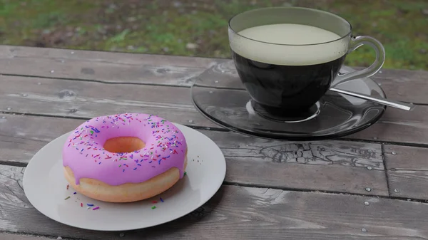 A cup of strong coffee with a delicious donut covered with sweet pink glaze on a table from boards  in the courtyard of the house