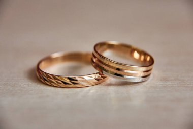 Gelin ve damat için iki altın alyans bej ahşap dokuda bulunur. Metin için boşluk.