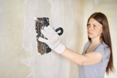 Duvarlara macun ya da spatulayla macun yapıştıran bir kadın. Tamir işleri, dekorasyon bina konsepti, inşaat..