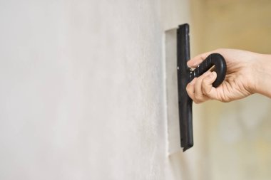 Elinde beyaz macunla Spatula. İşçi duvara alçı yapıştırıyor. Tamir işleri. Alçılama duvarı. Yakın plan..