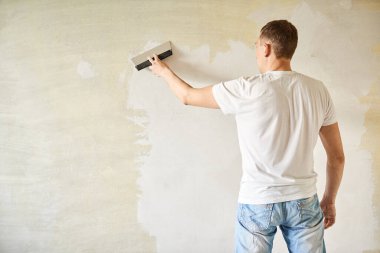 Duvarlara macun ya da spatulayla macun yapıştıran bir adam. Tamir işleri, dekorasyon bina konsepti, inşaat..