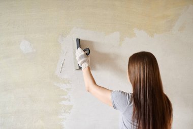 Duvarlara macun ya da spatulayla macun yapıştıran bir kadın. Tamir işleri, dekorasyon bina konsepti, inşaat..