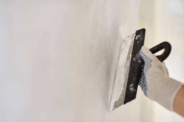 Spatula with putty in hand. Worker puts of plaster on wall. Repair work, decoration building concept, construction.