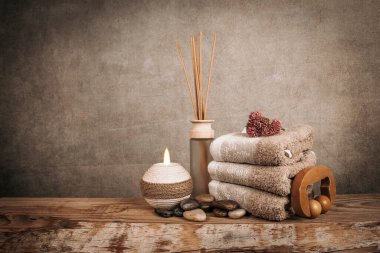 Kaplıca malzemeleri, aroma çubukları, taşlar, havlular, ahşap bir arka planda deniz kabuğu.