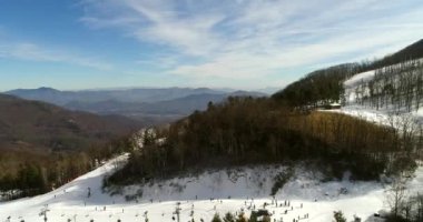 Güneşli bir günde karla kaplı kayak yolunun hava görüntüleri.