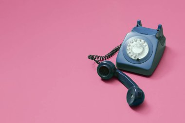 Kaldıraç ahizeli antika mavi döner telefon. Pembe arka planda, fotokopi alanı ve sağ tarafta kompozisyonu olan metin için yer var..
