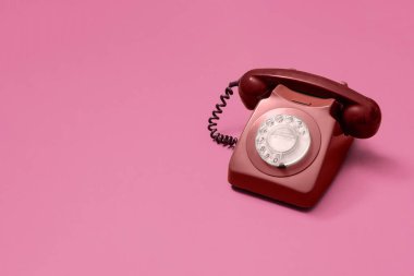 Pembe arka planda eski, pembe bir döner telefon. Fotokopi alanı ve sağ tarafta kompozisyonu olan metin için yer var.