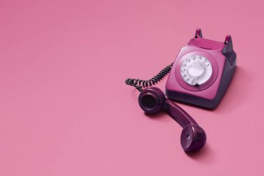 Fotokopi alanı ve sağ yan kompozisyonu olan metin için odası olan pembe arka planda kaldırılmış eski, pembe bir cep telefonu..