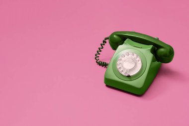 Pembe arka planda antika yeşil döner telefon. Fotokopi alanı ve sağ tarafta kompozisyon olan metin için yer var..
