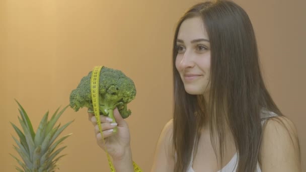 Flicka visar hälsosam livsstil hålla broccoli i händerna och ler — Stockvideo