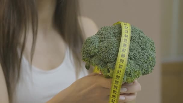 Broccoli en geel lint in de handen van een mooi meisje — Stockvideo