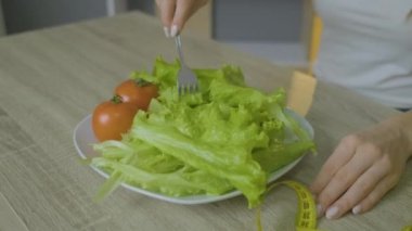 Kafkas görünümlü bir kadın masaya oturur ve lahana yaprakları yer, diyete yapışır.