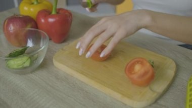 Kız masaya oturur ve domates doğrar.