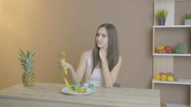 Женщина на диете с тарелкой, полной измерительной ленты — стоковое видео