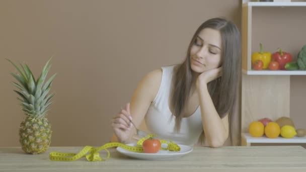식탁에 앉아 있는 여자는 토마토를 먹는다 — 비디오