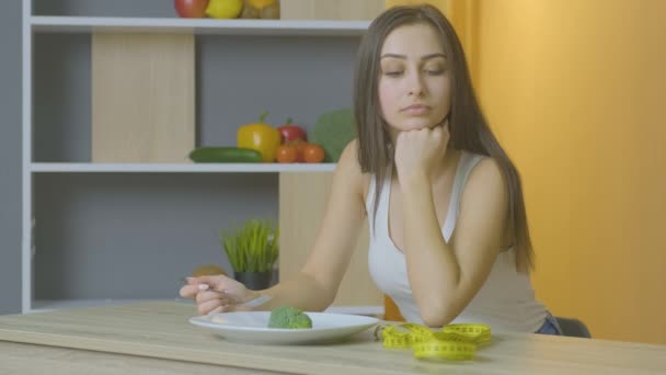 Vrouw leunde op de tafel en kijkt naar de broccoli — Stockvideo