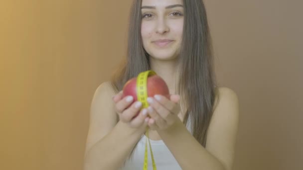 Mujer en la mesa sosteniendo manzana y cinta métrica sonriendo a la cámara — Vídeos de Stock