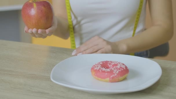 Καυκάσια κοπέλα κοιτάζει το τραπέζι με ευχαρίστηση να φάει ένα μήλο και σπρώχνει μελόψωμο — Αρχείο Βίντεο