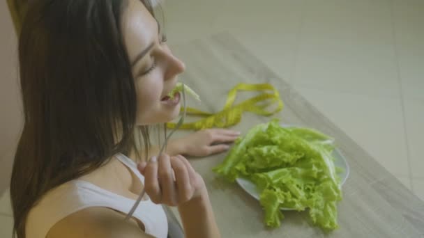 La mujer se sienta a la mesa y come hojas de col se adhiere a una dieta — Vídeo de stock