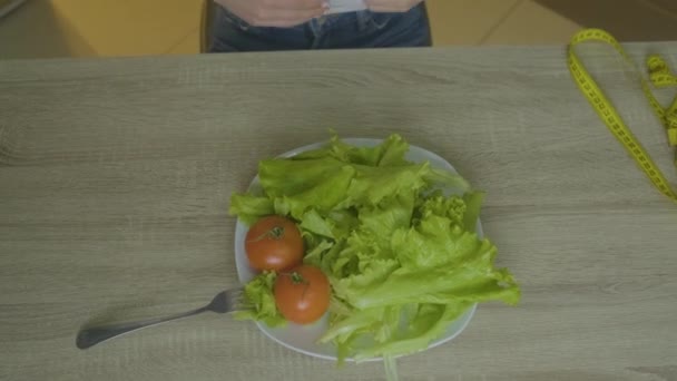 Mulher senta-se em uma mesa e pega seus vegetais — Vídeo de Stock