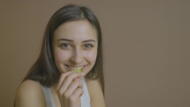 Flicka sitter vid ett bord och äter en gurka följer en diet — Stockvideo