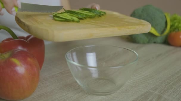 Chica sentada a la mesa mueve pepino en rodajas en un plato — Vídeos de Stock