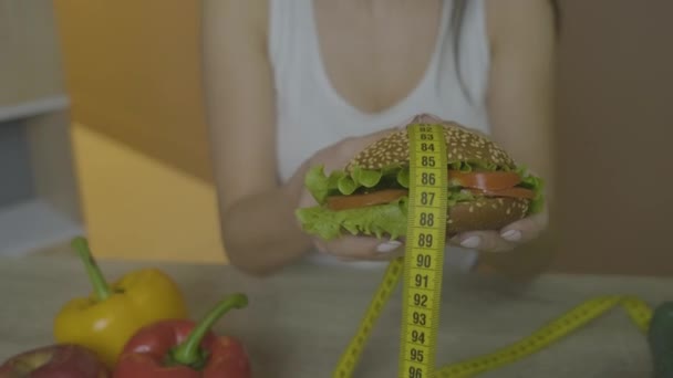 Elinde hamburger tutan bir kadın. Yakın çekim çekiliyor — Stok video