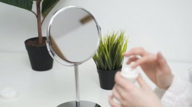 Kız parlak odada krem sürüyor.